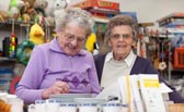 Foto: Eine Seniorin zwischen den Regalreihen in einer Kleiderkammer.